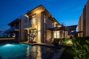 a house with a swimming pool in front of it at Wyndham Garden 3Br Villa 5star Resort Beachfront in Cam Lâm +18 photos