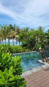 a swimming pool with palm trees and the ocean at Wyndham Garden 3Br Villa 5star Resort Beachfront in Cam Lâm
