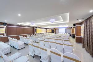 a conference room with white chairs and a podium at T S Royal Grand Hotel in Bengaluru