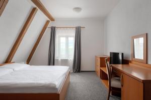 a bedroom with a bed and a desk and a mirror at Hotel Pohoda in Staré Město