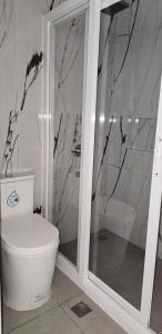 een badkamer met een wit toilet en een douche bij Leribi Suites and Restaurant in Ulot