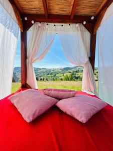 a red bed with pillows on it with a window at A Frame Panoramic Apuseni in Bistra