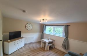 a living room with a tv and a clock on the wall at Millburn Chalet in Inverkip