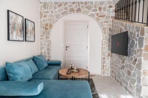 a living room with a blue couch and a stone wall at Aegean Nest in Mytilene