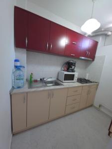a kitchen with red cabinets and a sink and a microwave at Garsoniera-studio in Zalău in Zalău