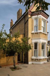 an old brick house with a tree in front of it at Lin Song House South London Garden Room Getaway in London