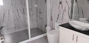 een zwart-witte badkamer met een douche en een wastafel bij Leribi Suites and Restaurant in Ulot