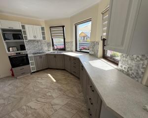 a kitchen with white cabinets and a large window at La Pop Cu Drag in Ocna Şugatag