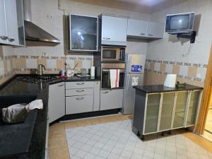 a kitchen with white appliances and a tv on the wall at Appartement Moderne 3 Chambres Avenue Hedi Nouira Cité Ennasr Tunis in Ariana