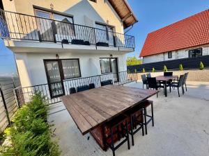a patio with a wooden table and chairs on a balcony at La Pop Cu Drag in Ocna Şugatag