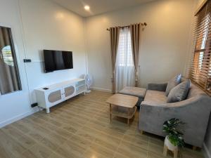 Una sala de estar con un sofá y un televisor. en เพชรไพลินรีสอร์ทสามร้อยยอด, en Sathani Sam Roi Yot