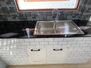 Una cocina con fregadero y gabinetes blancos. en เพชรไพลินรีสอร์ทสามร้อยยอด, en Sathani Sam Roi Yot