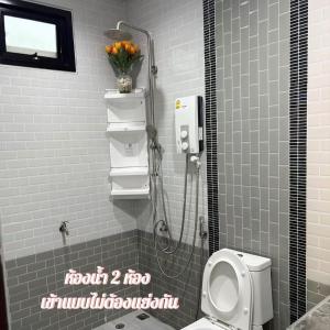 a bathroom with a shower with a toilet and flowers at 784 poolvilla พูลวิลล่า in Ban Khao Rup Chang