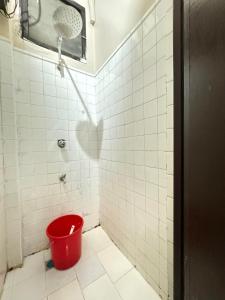Un cubo rojo en un baño de azulejos blancos. en 88Ap Lodging House San Marcelino, en Manila