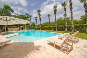 a swimming pool with two chairs and an umbrella at Espectacular Apto en Casa de Campo Los Altos 3 in La Romana