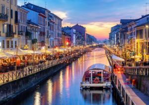 einen Fluss mit Booten in einer Stadt bei Sonnenuntergang in der Unterkunft Casa Celeste b&b Navigli in Mailand