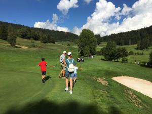 a group of people walking on a golf course at Albergo Centrale in Carbonare di Folgaria