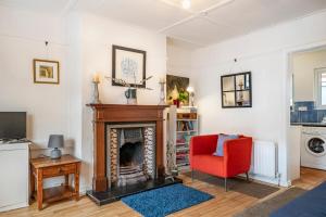 a living room with a fireplace and a red chair at Cosy and central Belfast House in Belfast