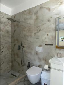 Un baño con inodoro blanco y ducha. en Hotel Ridal, en Vlorë