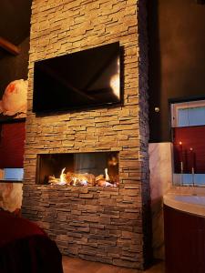 a stone fireplace with a tv on top of it at Wellness Tuin - Boudoir Suite - Ultieme Partner Beleving met Jacuzzi en Openhaard en privé Sauna in Romantische stijl in Horst
