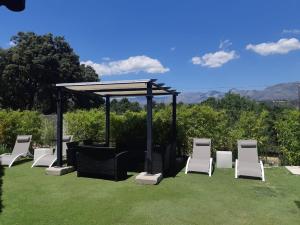 a group of white chairs and a gazebo at Casa Rural La Casita Roja in Burgohondo