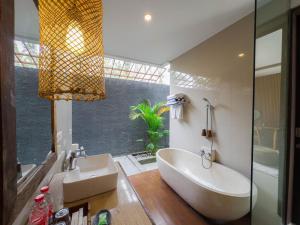 een badkamer met een groot bad en een wastafel bij Kakul Villas & Suites Ubud in Ubud