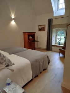 a bedroom with two beds and a window at Les Communs de Chiffrevast in Tamerville