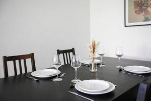 a black table with plates and wine glasses on it at Appartement Moderne, À la Passerelle des Trois Pays, HUNINGUE CENTRE in Huningue