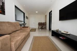 a living room with a couch and a flat screen tv at Apart Hotel Barra Bela Barra da Tijuca in Rio de Janeiro