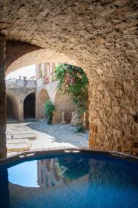 an outdoor swimming pool with a stone wall and water at La galeria de dalt in Rupiá