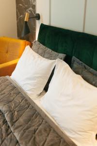 a bed with white pillows and a green couch at Beach Apartment in Batumi