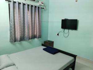 a bedroom with a white bed and a tv at Royal 2 Bed Room Apartment -Opp Mattuthavai Bus stand Madurai in Madurai
