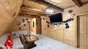 a living room with a couch and a tv on a wall at A Frame Panoramic Dundy in Dealu Muntelui