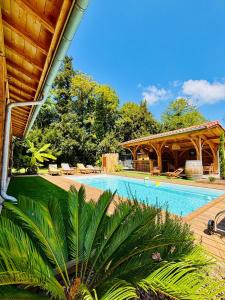 a swimming pool next to a house with a pavilion at Villa La Forge in Parentis-en-Born