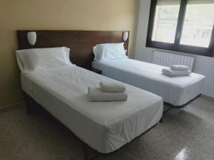 two beds in a hotel room with towels on them at Hostal Restaurant Sant Marçal in Amer +7 photos