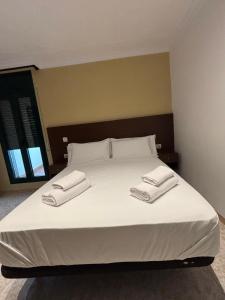 a large white bed with two towels on it at Hostal Restaurant Sant Marçal in Amer