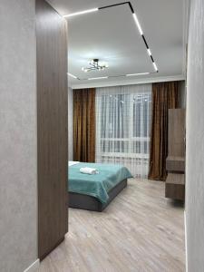 a bedroom with a bed and a large window at Панорамная евродвушка комфорт-класса in Almaty