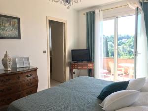 a bedroom with a bed and a television and a balcony at Bastide Rose de Mai in Le Rouret