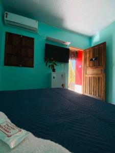 a bedroom with a bed with blue walls and a television at Pousada Villa Maria Corumbau in Corumbau +15 photos