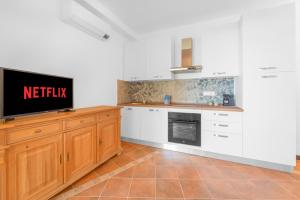 a kitchen with white cabinets and a flat screen tv at -Vista Mare- Casa con piscina e spiaggia a 300 MT in Liscia di Vacca