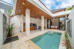 an indoor swimming pool in a house with a kitchen at Bramasta Villa in Ubud