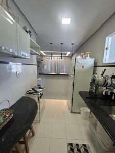 a kitchen with a refrigerator and a table in it at Casa aconchegante em Aracaju na Aruana in Aracaju