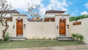 a white house with two wooden doors at Bramasta Villa in Ubud