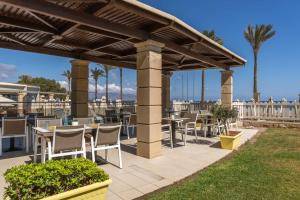 a patio with tables and chairs under a pergola at Caldera Beach in Platanias