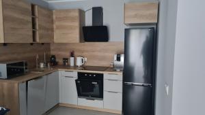 a kitchen with a black refrigerator and white cabinets at Zuzia Apartments in Chojna