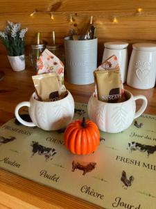 a table with three tea cups and a pumpkin at Jacob's Den Cosy pod with hot tub in Swansea