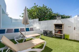 a patio with chairs and an umbrella and a grill at VIBESOL Apartments in Playa Honda