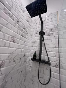eine Dusche in einem Badezimmer mit einer weißen Ziegelwand in der Unterkunft Escapade Élégante climatisé in Longué + 2 Fotos