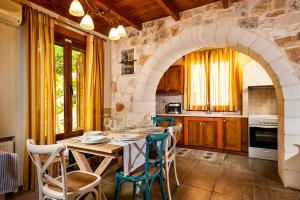 a kitchen with a table with chairs and an archway at Villa Eftichia in Stalos