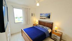 a bedroom with a bed with blue sheets and a window at Apto Vista Impecável - Praia do Forte in Cabo Frio +16 photos